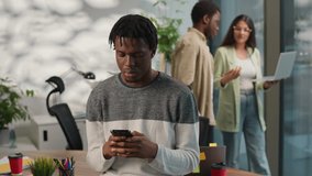 African American concentrated man informal business startup worker male guy businessman using mobile phone addict smartphone chatting two multiracial colleagues with laptop talking walk on background - Powered by Shutterstock - Get 15% off with code: PIKWIZARD15