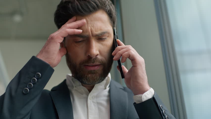 Close up Caucasian businessman worried anxiety business man in office portrait talking mobile phone discuss bad news failure problem communicate male entrepreneur stressed talk call looking in window