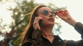 Stylish serious Caucasian woman businesswoman talking mobile phone finish call using smartphone checking message at street female girl business discuss conversation in autumn city wearing sunglasses - Powered by Shutterstock - Get 15% off with code: PIKWIZARD15