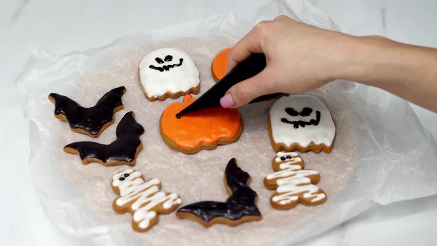 Women's hands coloring Halloween cookies. Halloween concept. Holiday atmosphere. Preparing for the Halloween party. 4k footage.