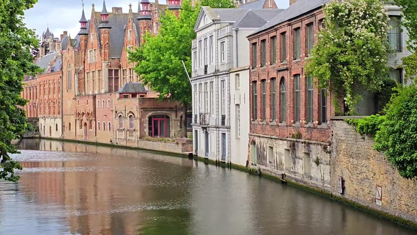 Rippling waters and reflections in the beautiful historic canals of Bruges, Belgium. Handheld panning motion.