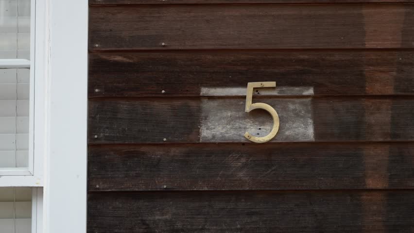 An elegantly crafted and visually appealing view of house number 5 prominently displayed on a rustic wooden wall