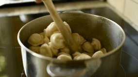 Close-up of a wooden spoon stirring delicious dumplings boiling in a metal pot on a modern induction stovetop. A shot of home cooking. FullHD footage. - Powered by Shutterstock - Get 15% off with code: PIKWIZARD15