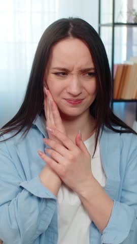 Young ill woman at home suffering from severe toothache, holding cheek painfully, tiredly searching for painkiller pills. Caucasian sick girl experiencing strong discomfort, exhausted by dental pain