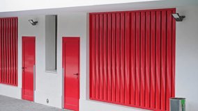 Colorful building exterior with vibrant red and blue doors under a bright sunny sky, showcasing modern design and urban architecture. - Powered by Shutterstock - Get 15% off with code: PIKWIZARD15