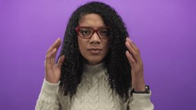 Woman wearing red glasses and turtleneck sweater adjusts curly hair and massages temples in studio; stress fatigue frustration. - Powered by Shutterstock - Get 15% off with code: PIKWIZARD15