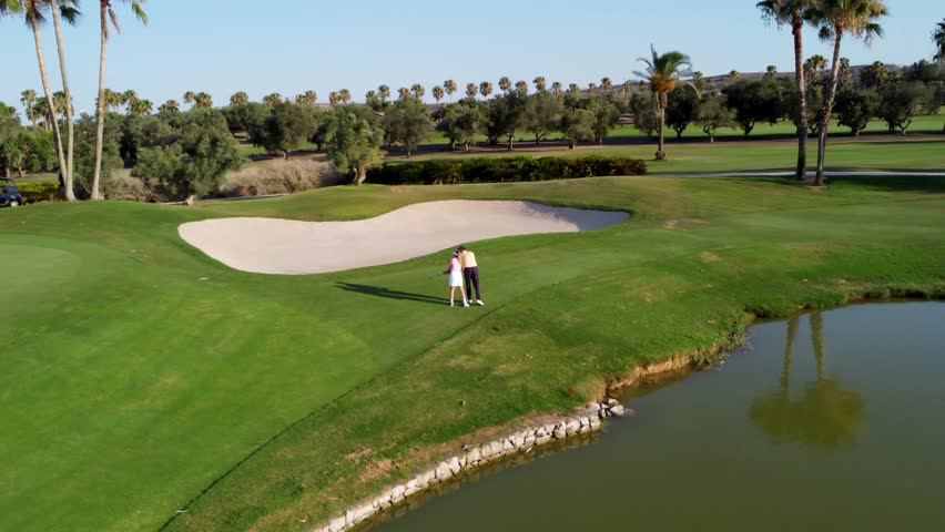 Golf instructor guiding a female golfer, providing tips and support during a lesson on a sunny day at the golf course - Powered by Shutterstock - Get 15% off with code: PIKWIZARD15