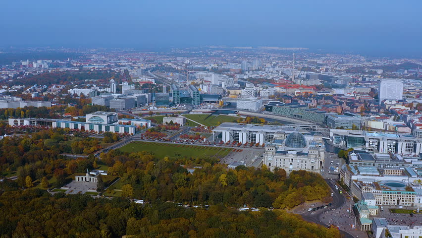 4K drone panorama of Berlin’s government district - Reichstag with glass dome, Bundeskanzleramt, Tiergarten and Berlin Hauptbahnhof glowing in autumn light across Germany’s capital skyline.