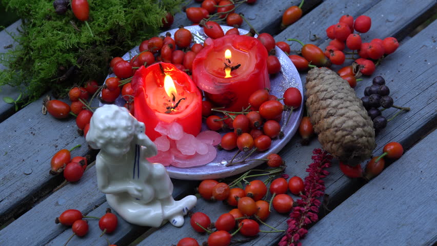 Burning red candles, hips and moss  on a grey background. A tiny angle. Christmas decoration.