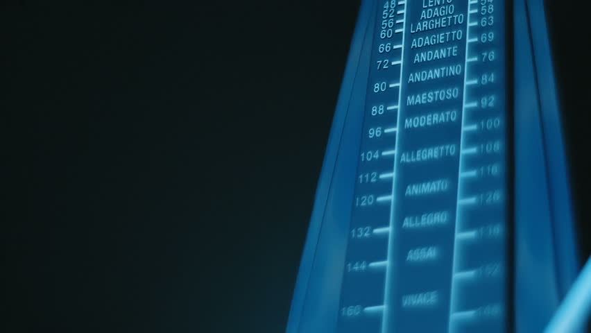 New, modern, shiny, black metronome, with a swinging pendulum, accurately beats in time, helping the musician not to lose the rhythm, on a black background. Closeup. Macro. Slow mo, slow motion