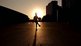 The silhouette of a little boy stuffing a ball in a city park in summer at sunset. The child is engaged in football.  - Powered by Shutterstock - Get 15% off with code: PIKWIZARD15