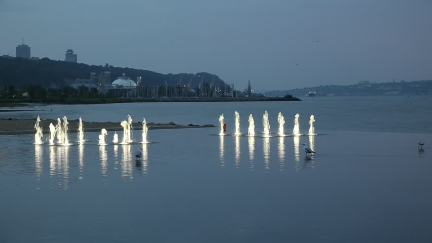 Seagulls wading in a shallow pool with fountains at the Beach Station during a cloudy sunrise, Quebec City, Québec, Canada