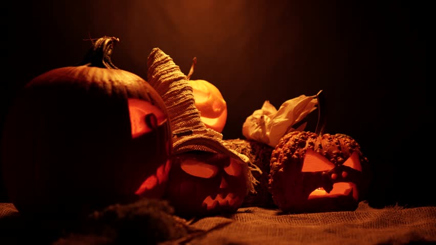 Halloween pumpkins dark arrangement for welcome celebration front yard decoration. All Saints day spirits Infernal and mystical background, burning flickering candles in the carved heads. - Powered by Shutterstock - Get 15% off with code: PIKWIZARD15