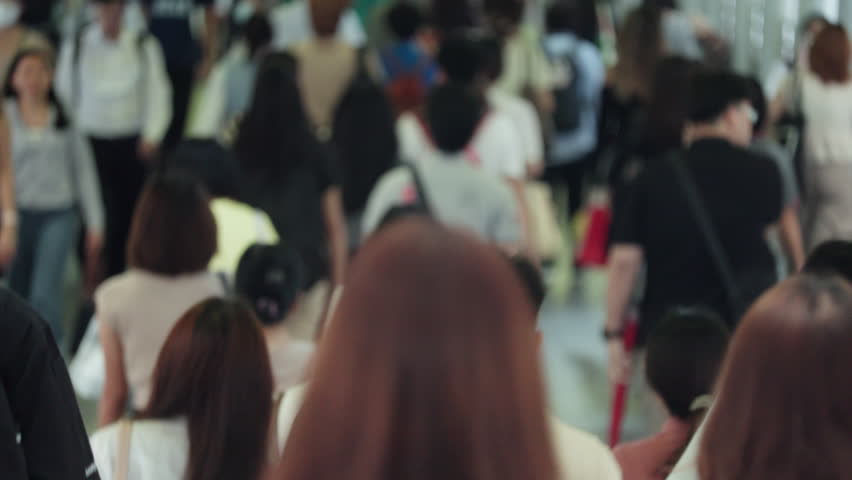 Bangkok Crowded urban walkway showcasing diverse pedestrians moving through a bustling mall environment. Focus on individuals from various angles demonstrating lively foot traffic. High-energy