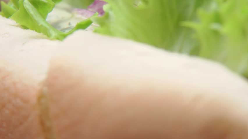 Close-up of a hot dog cut in half. The cross-section reveals a juicy grilled sausage, a soft bun, and a generous layer of sauce. Perfect for food blogs, menus, or fast food content