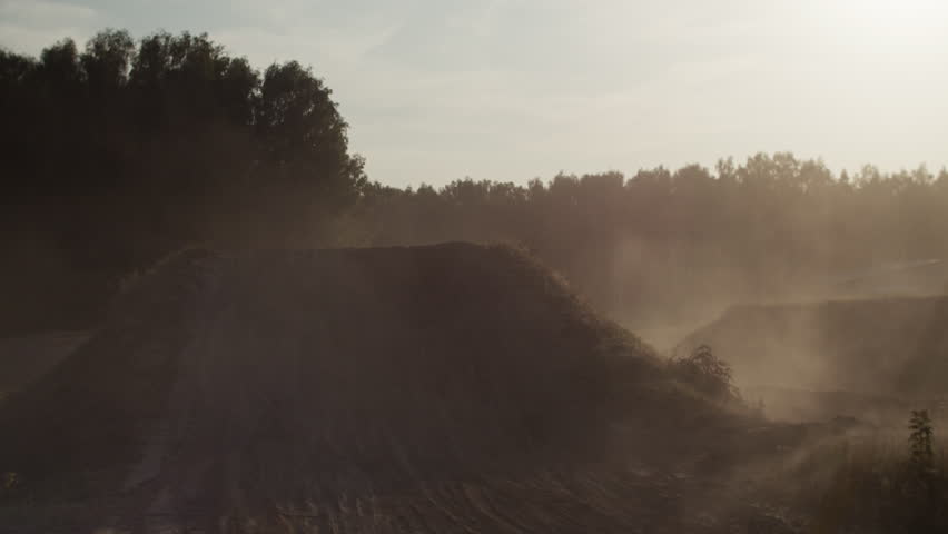 Motorcyclist in helmet jumping with motorbike over dirt ramp