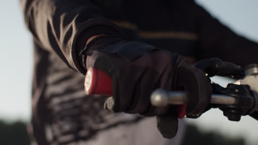 Biker hand in glove holds motorcycle handle and brake lever