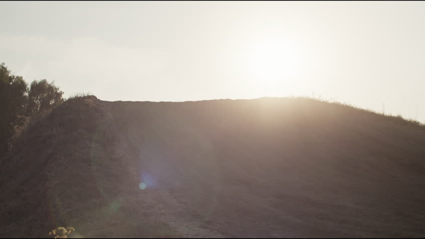 Courageous rider in helmet jumps with bile on ramp at sunset