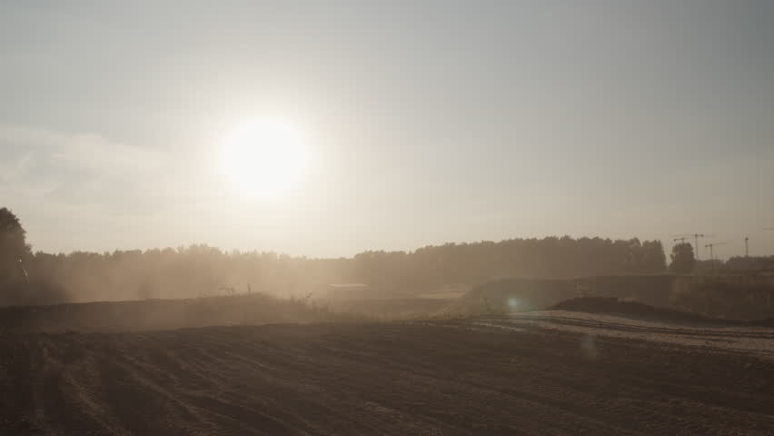 Silhouette of biker jumping with motorcycle from behind low hill