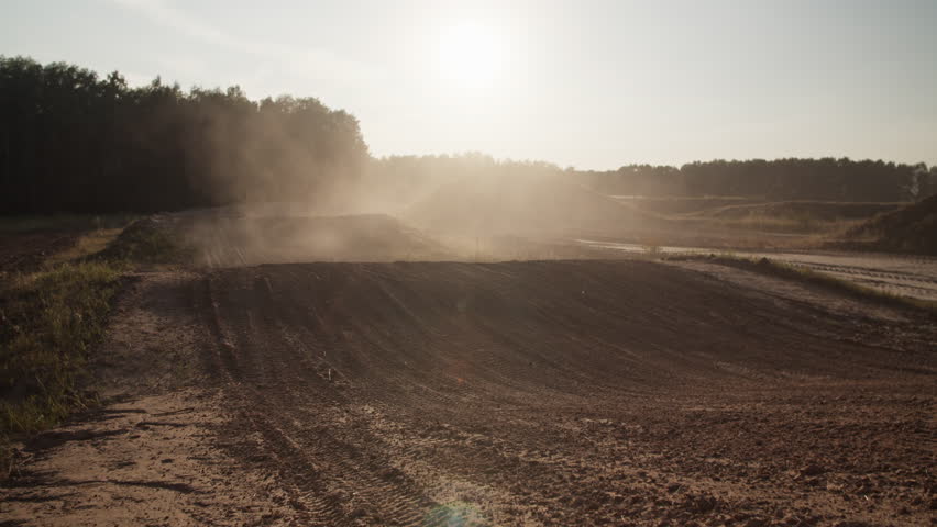 Brave sportsman jumps on motorcycle riding along hilly ground