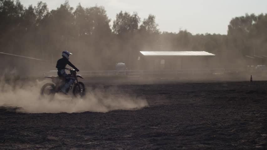 Trained biker in helmet drifts with racing motorcycle in field