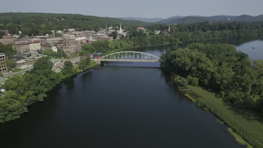 Drone lowers over Connecticut River with Brattleboro in the distance in the early morning