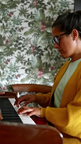 Professional female pianist performing melodic composition on vintage wooden piano, surrounded by tropical floral wallpaper, expressing musical passion and creative emotion