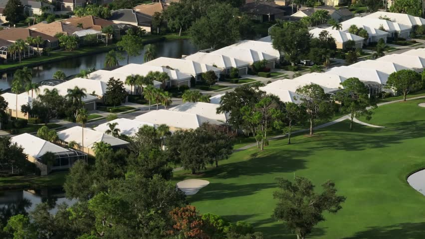Luxury houses in golf club of Bradenton, Florida. Aerial wide shot. Sunset time with palm trees and golf course.