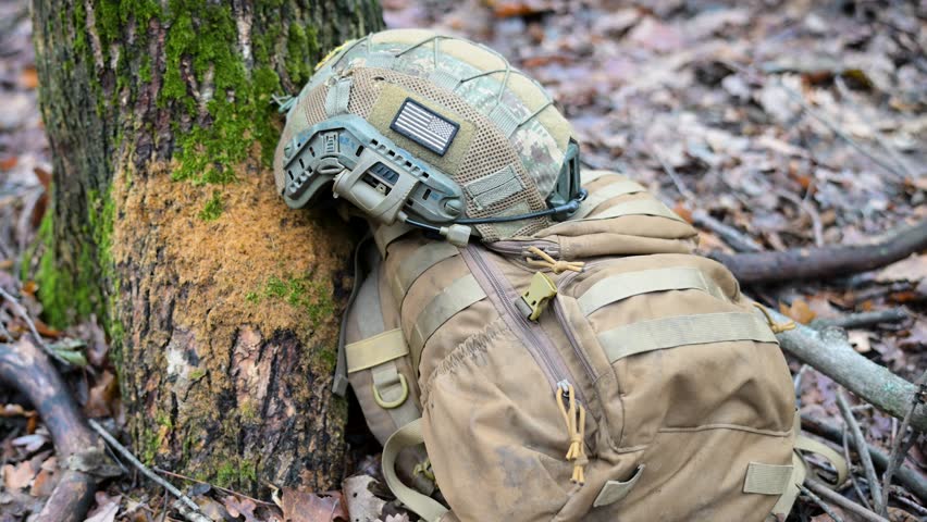 War in Ukraine: Gear of a foreign volunteer soldier during a pause in a tactical training drill. A helmet with a US flag patch and a backpack lie ready in a forest.