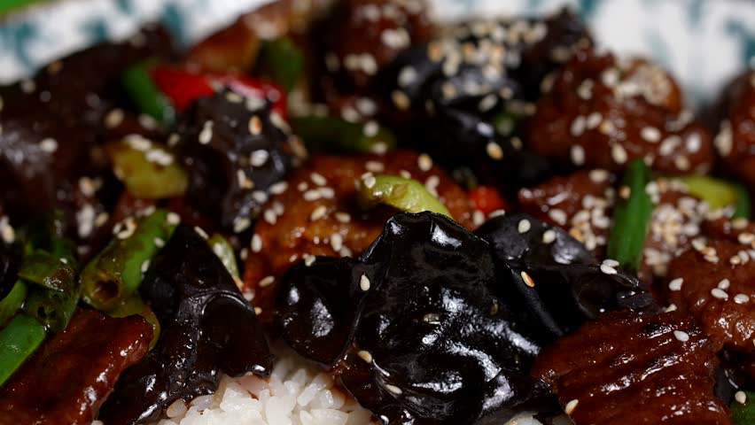 Rich stir-fry with beef slices, glossy mushrooms, green beans, red peppers, and sticky white rice.