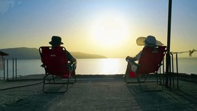 Romantic couple sitting on a balcony, enjoying the golden sunset over the sea, with distant islands under a clear sky - Powered by Shutterstock - Get 15% off with code: PIKWIZARD15