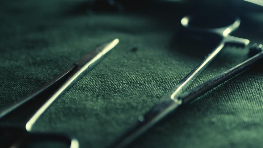Surgical medical instruments laid out on green linen CLOSE-UP slide reveal
