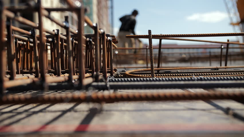 Steel rebar at construction site with worker in background