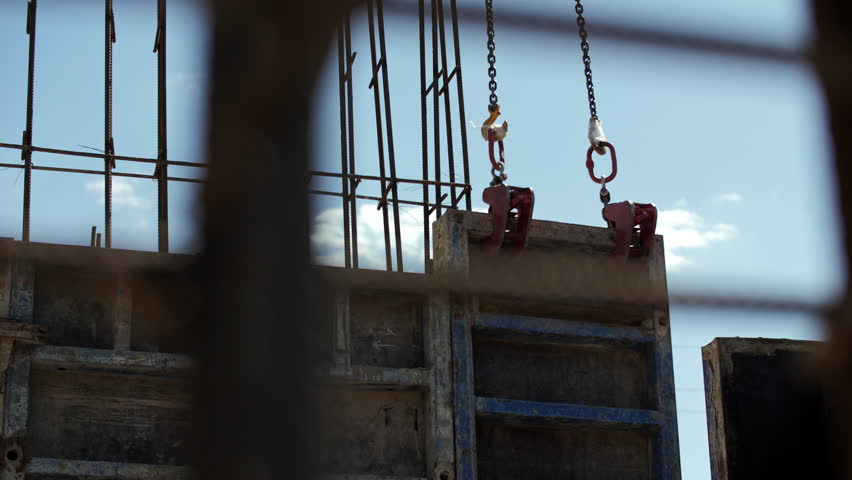 Crane lowering formwork at construction site