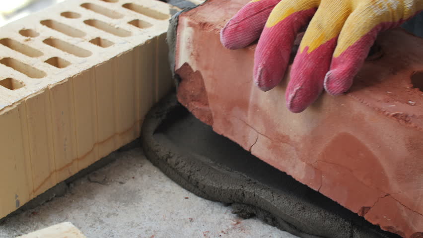 Worker laying brick on mortar at construction site
