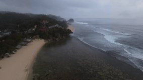 16:9 2K 30fps aerial drone view of Yogyakarta coastline at dusk. Gentle waves hit the shore, with seaside houses surrounded by a soft misty atmosphere, creating a calm and dreamy tropical scene. - Powered by Shutterstock - Get 15% off with code: PIKWIZARD15