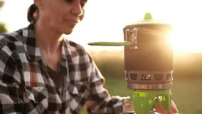 Girl Boiling Water On A Portable Camping Gas Stove To Cook Dinner Outdoors At Sunset - Powered by Shutterstock - Get 15% off with code: PIKWIZARD15