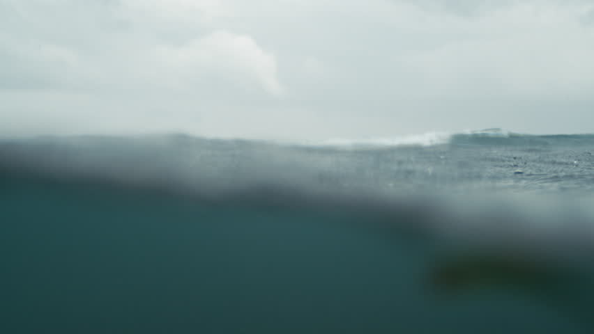 Raindrops fall in slow motion creating dynamic textures on ocean surface