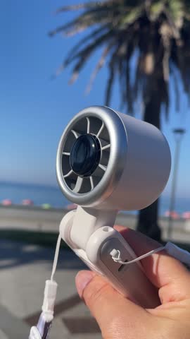 Portable wireless fan for outdoors and home. Modern lifestyles, mobile technology, travelling in summer. Global warming.
