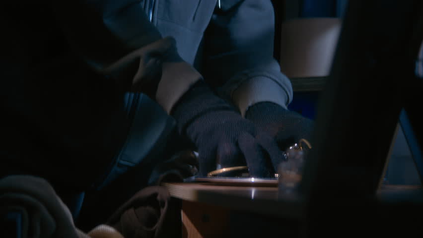 Two burglars dressed in total black cooperating while stealing jewelry during housebreaking at night