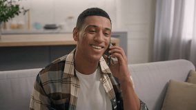 Positive African American man male guy enjoying good communication with smartphone in living room talking mobile phone smiling conversation with telephone satisfied laughing conversation at home couch - Powered by Shutterstock - Get 15% off with code: PIKWIZARD15