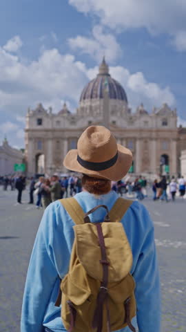  A girl tourist in a hat and with a backpack walks along as she admires the iconic St. Peters Square in Vatican City, Italy, 29.04.2025