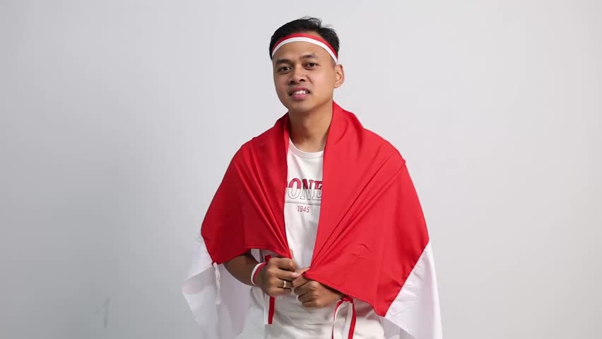 Indonesian man celebrate Indonesian independence day on 17 August by holding the Indonesian flag isolated over white background