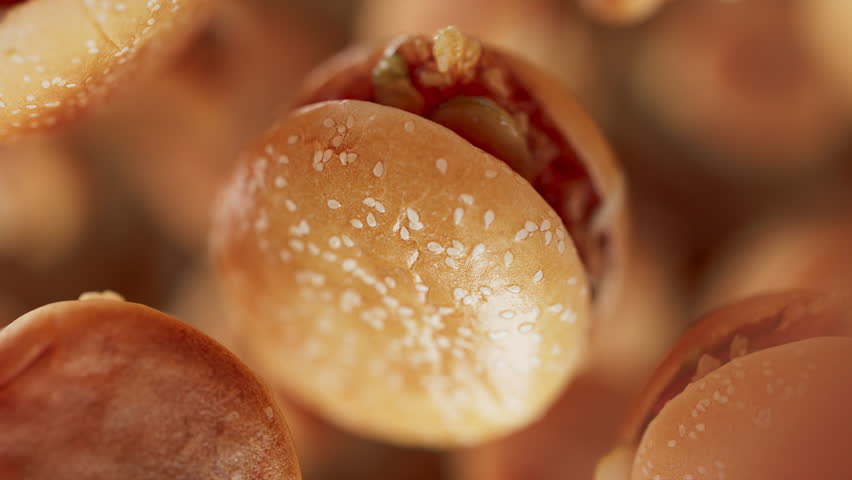 Animation of a group of burgers. Many burgers slowly rotate in the background in space. Horizontal composition. Defocus. Close-up.