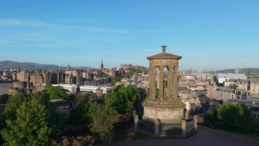 As the drone ascends behind Dugald Stewart Monument, the breathtaking view of Edinburgh’s skyline, castle, and landmarks unfolds beneath the golden light.