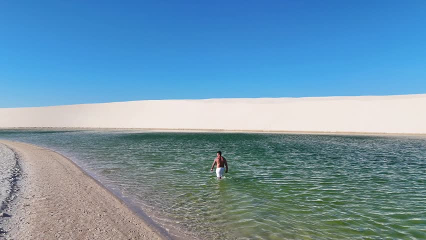 orbits a man in the blue lake of Lençóis Maranhenses