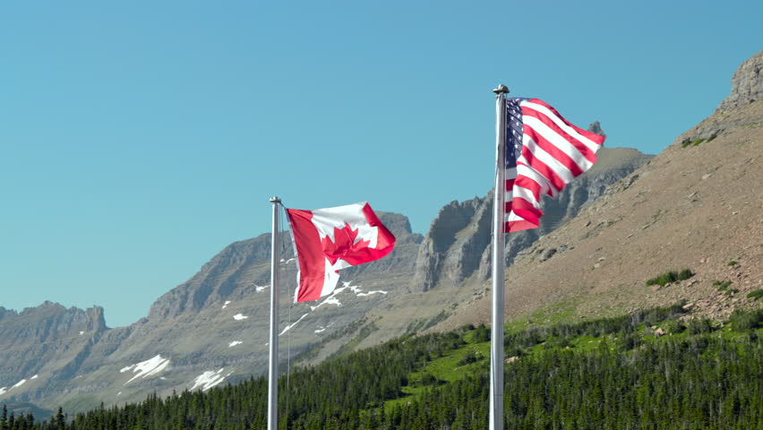 The sight of the Canadian and American flags fluttering against a mountain backdrop symbolizes the unity and friendship between these nations, highlighting their cultural ties and shared history