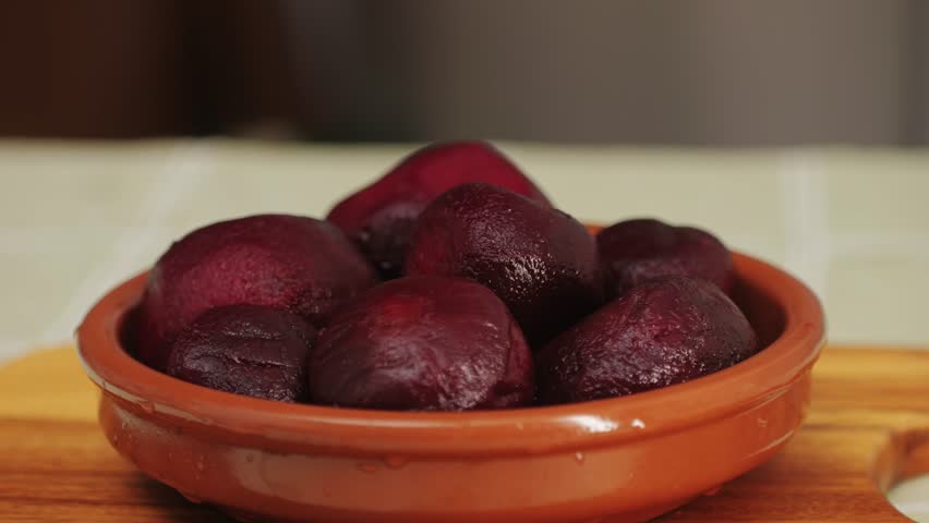 Raw peeled vegetable beet in plate on wooden table close-up. Preparing raw vagetables food for cooking. Cooking traditional Russian Borsch. 