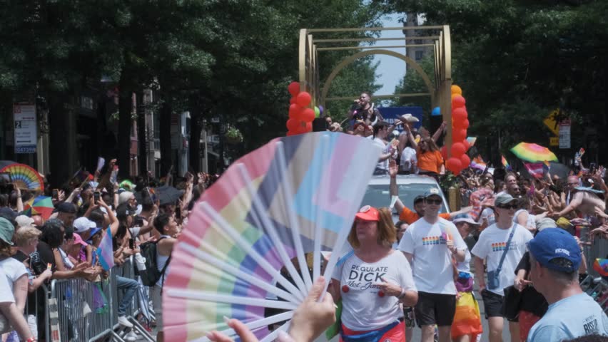 New York, NY USA June 29 2025: People marching in a Pride parade holding Progress Pride flags. Public event celebrating LGBTQ+ rights and inclusivity.