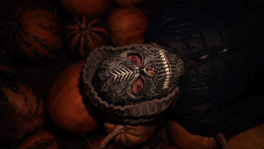 Halloween monster at night lying on pumpkins. people with Halloween masks, dramatic film effect. dark atmosphere, scattered pumpkins, and ominous vibe, is perfect for a spooky Halloween theme.